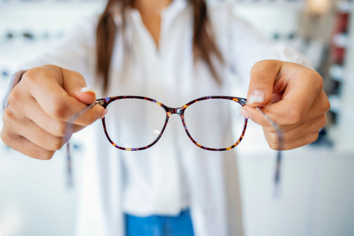 Mujer sosteniendo gafas para visión borrosa